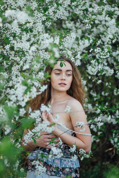 Una hermosa chica con un vestido se encuentra junto a un autobús de cerezas en flor