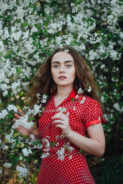 Una hermosa chica con un vestido se encuentra junto a un autobús de cerezas en flor