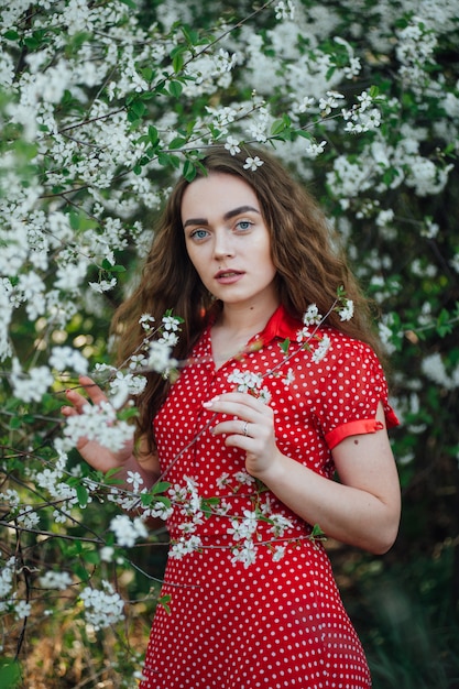 Una hermosa chica con un vestido se encuentra junto a un autobús de cerezas en flor