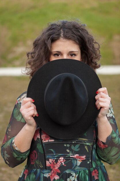 Hermosa chica con vestido de flores un sombrero negro