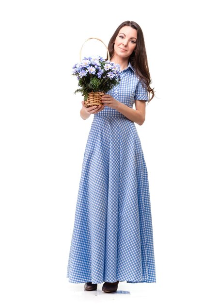Hermosa chica con un vestido en una jaula azul con crisantemos de flores en las manos sobre un fondo blanco