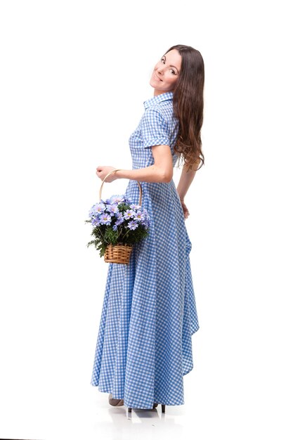 Hermosa chica con un vestido en una jaula azul con crisantemos de flores en las manos sobre un fondo blanco