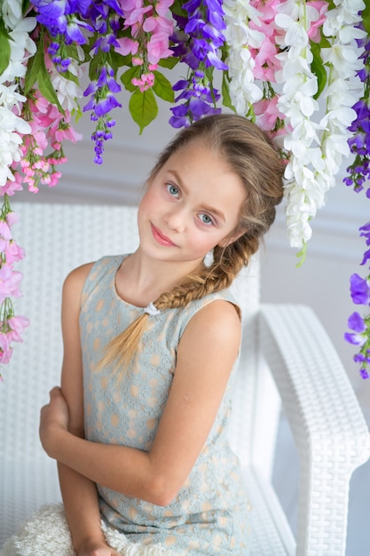 Foto hermosa chica en un vestido ligero posando con arbustos en flor.