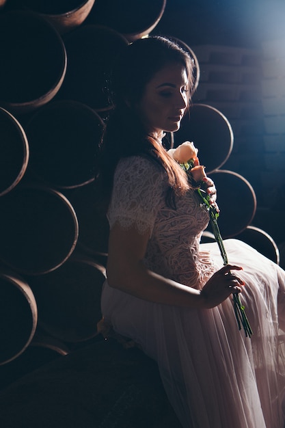 Hermosa chica en un vestido ligero con ramo de flores entre tubos de metal