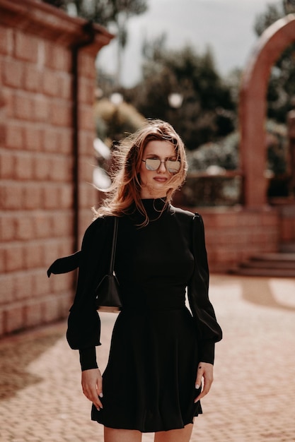 Hermosa chica con un vestido negro en la calle