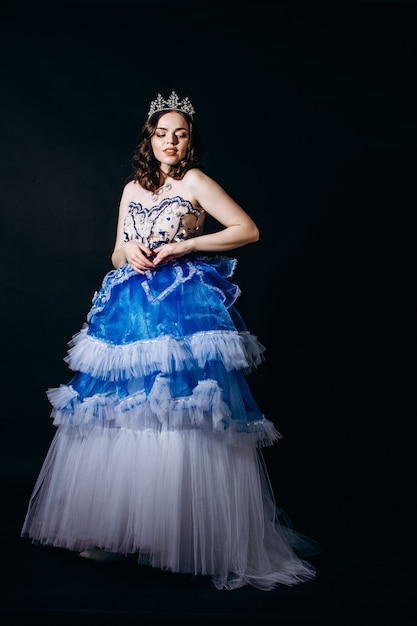 Hermosa chica en un vestido de noche largo azul sobre un fondo negro