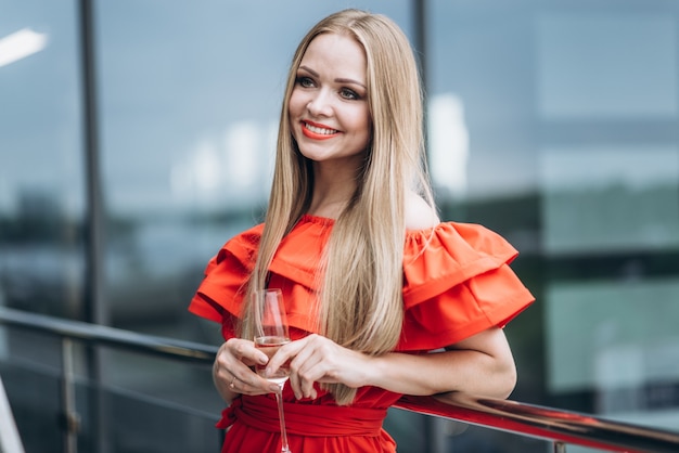 Hermosa chica en un vestido rojo con una copa de champán