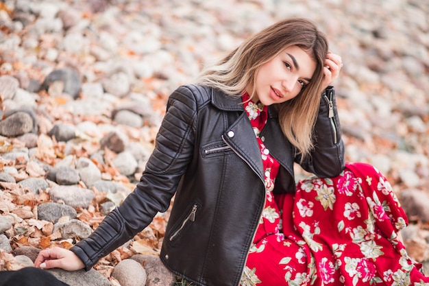 Hermosa chica en un vestido rojo sentada en la orilla rocosa