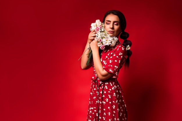 Hermosa chica con un vestido rojo sobre un fondo rojo con flores.