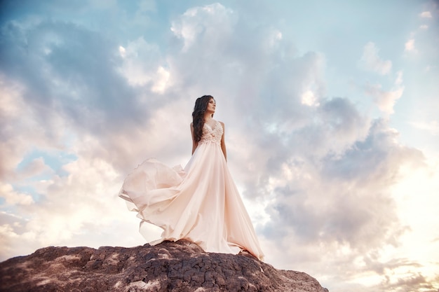 Hermosa chica con un vestido de verano beige camina montañas