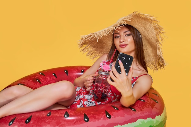 Hermosa chica en vestido de verano sombrero de paja con forma de anillo inflable de sandía con cocktai fresco ...