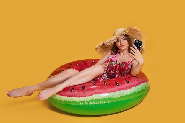 Foto hermosa chica en vestido de verano sombrero de paja con forma de anillo inflable de sandía con cocktai fresco ...