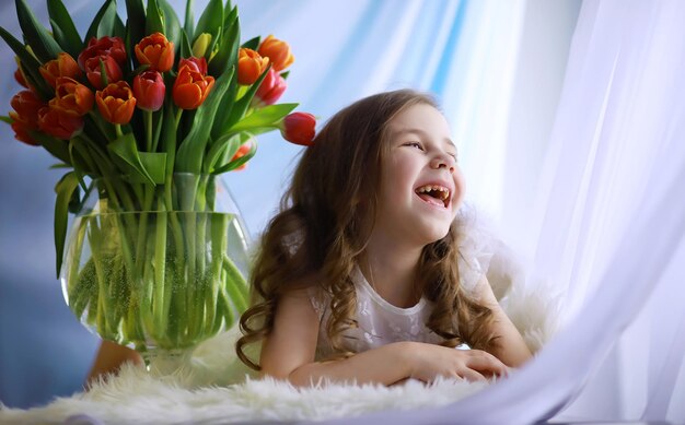 Hermosa chica con vestidos blancos con un magnífico ramo de los primeros tulipanes Día Internacional de la Mujer Chica con tulipanes