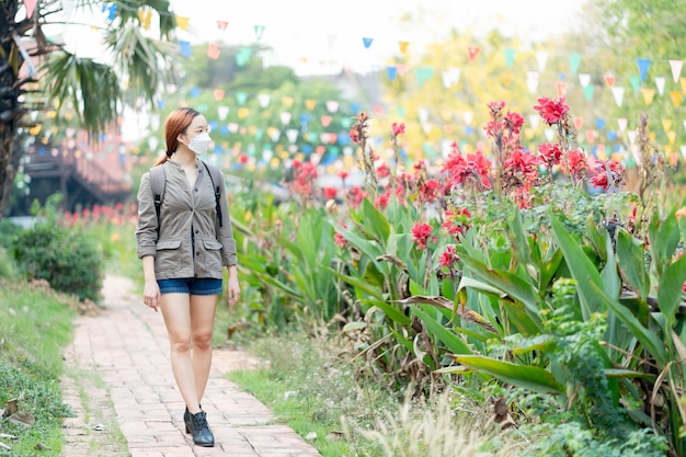 Hermosa chica viajera con máscara y mochila caminando por la carretera en ayothaya tailandia Concepto de relajación de vacaciones de viaje