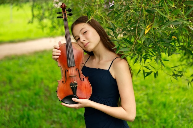 Hermosa chica con violín en la naturaleza.