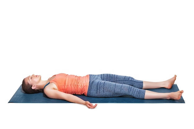 Una hermosa chica yogui en forma deportiva se relaja en el yoga asana savasana