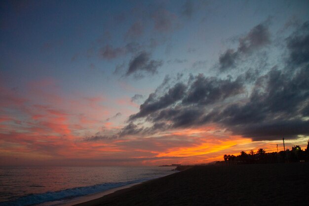 Hermosa y colorida puesta de sol luz cálida y muchas nubes olas del mar en la costa del mar