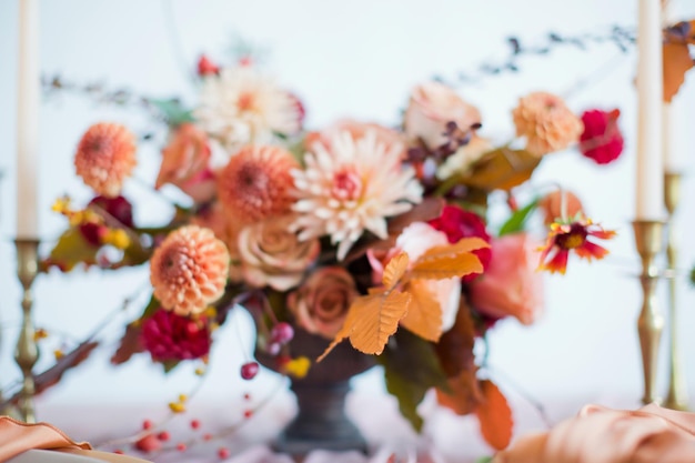 Hermosa composición floral con flores y bayas naranjas y rojas otoñales Ramo de otoño en jarrón vintage sobre una mesa de madera con tejido rosa y velas