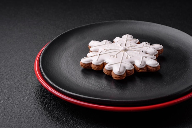 Una hermosa composición navideña que consiste en placas de cerámica, pan de jengibre y otros elementos de decoración de Año Nuevo sobre un fondo de hormigón oscuro
