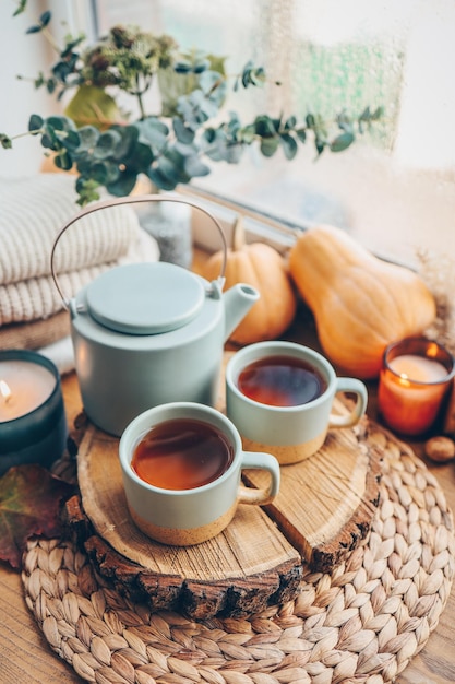 Hermosa composición otoñal con velas encendidas y una taza de té en el alféizar de la ventana