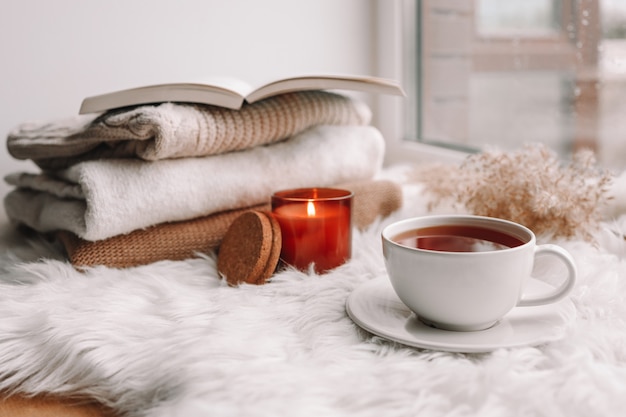 Hermosa composición otoñal con velas encendidas y una taza de té en el alféizar de la ventana