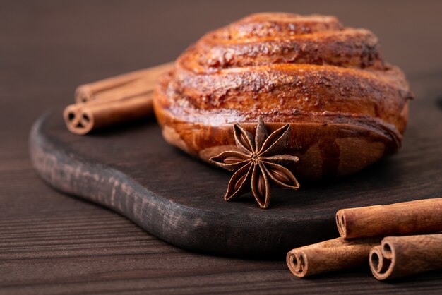 Hermosa composición de pan de canela en la mesa de madera oscura con palitos de canela alrededor y una estrella de anís. Hornear en casa