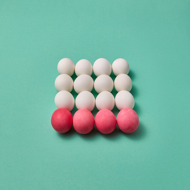 Hermosa composición de pascua hecha de huevos pintados de rosa y blanco sobre un fondo verde con copia