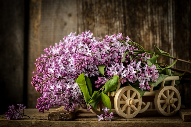 Hermosa composición con ramo de lilas en mesa vieja