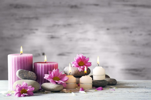 Hermosa composición con velas y piedras de spa sobre fondo de madera