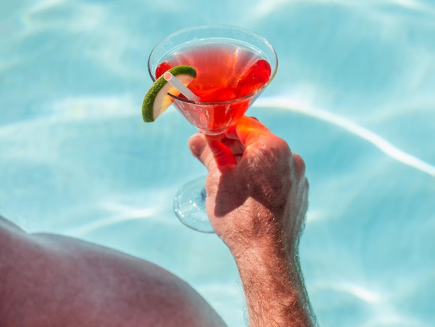 Hermosa copa con un cóctel refrescante y un hombre atractivo.