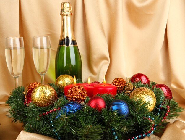 Hermosa corona de Navidad en composición con champán en la superficie de la tela dorada