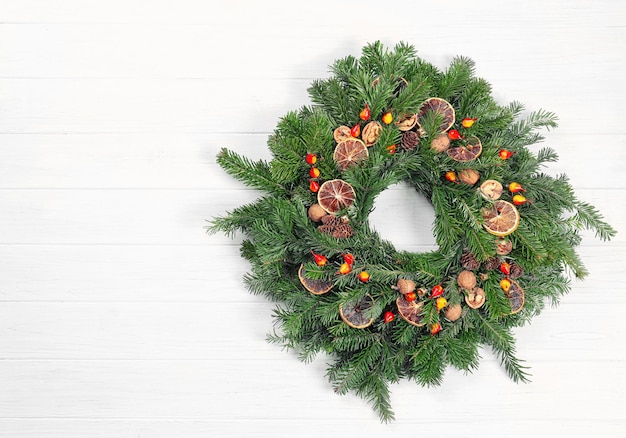 Hermosa corona de Navidad hecha por floristería profesional sobre fondo blanco de madera