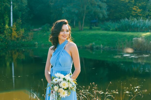 Hermosa dama de honor joven con el pelo rizado posando en la ceremonia de la boda