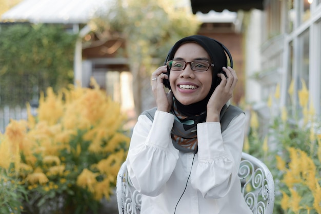 hermosa dama musulmana asiática ropa casual usando auriculares