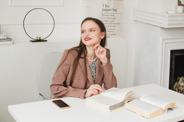 Hermosa dama de negocios sentada en la mesa con un libro