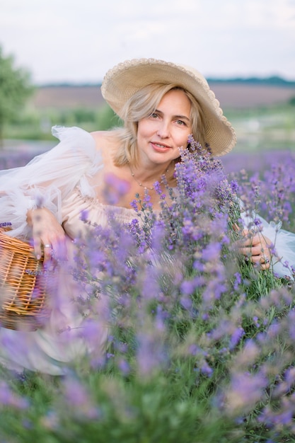 Hermosa dama rubia madura en campo de lavanda.