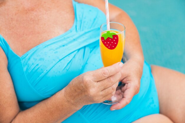 Hermosa dama senior tomando el sol y relajándose en una piscina privada durante el verano