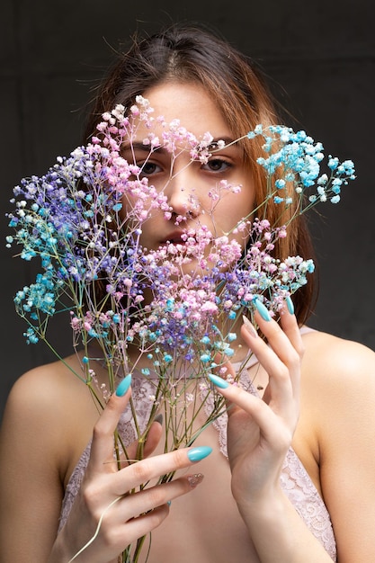 Una hermosa dama sexy en un elegante traje desnudo sostiene flores en sus manos Retrato de belleza de moda de una chica modelo de moda en el estudio