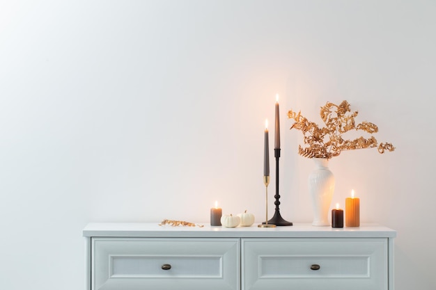 Hermosa decoración del hogar de otoño con velas encendidas en el interior blanco