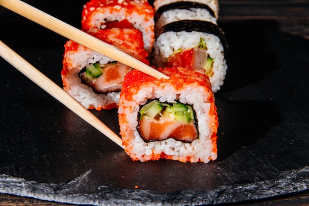 Hermosa y deliciosa variedad de rollos de sushi en un tablero de piedra.