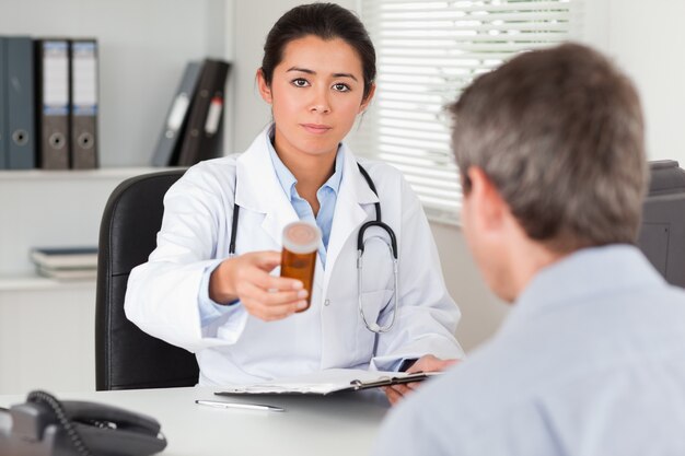 Hermosa doctora mostrando una caja de pastillas a la cámara