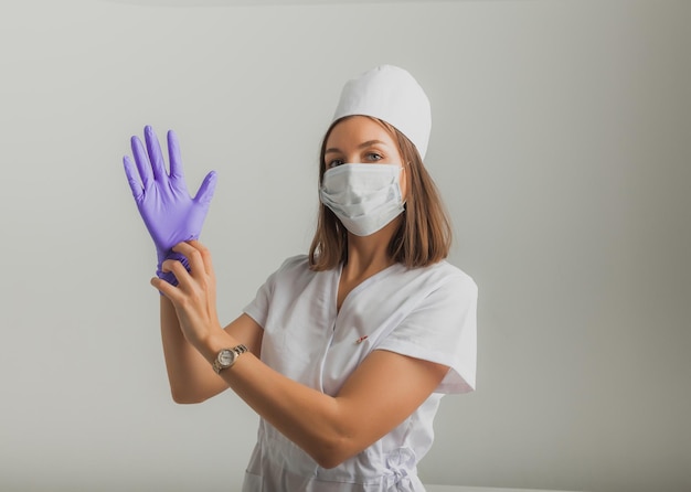 Una hermosa doctora o enfermera con una máscara protectora y guantes de goma sobre un fondo claro con copyspace. Concepto de salud