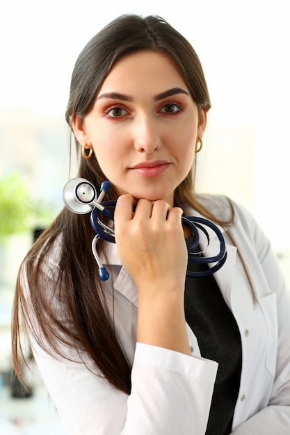 Hermosa doctora sonriente sentarse en el lugar de trabajo