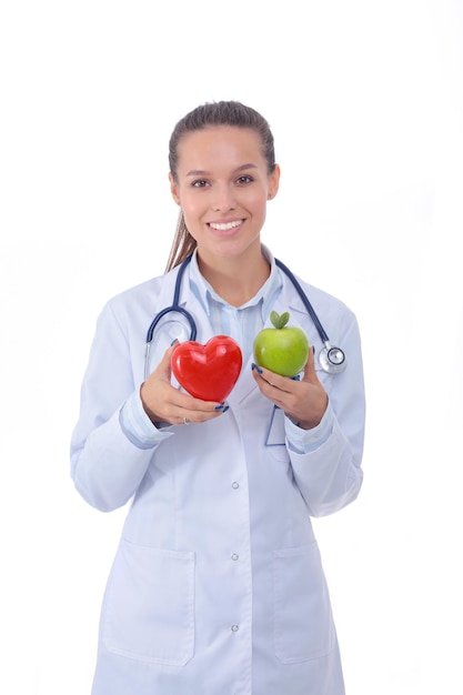 Hermosa doctora sonriente sosteniendo corazón rojo y manzana verde