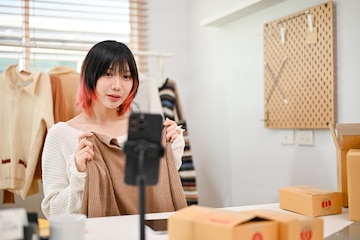 Hermosa dueña de una tienda en línea asiática que vende su ropa a través de  una transmisión en vivo | Foto Premium
