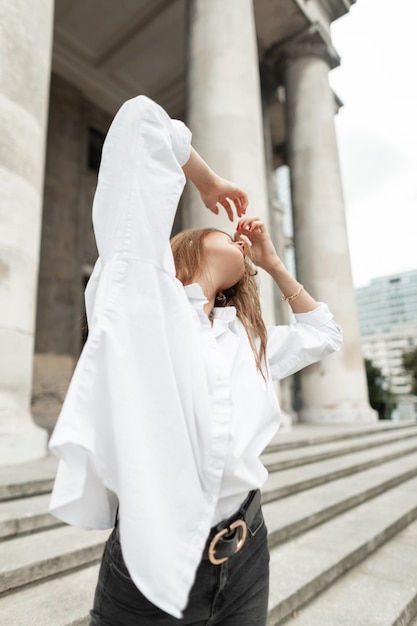 Una hermosa y elegante chica de negocios con un elegante atuendo con una camisa blanca camina y disfruta en la ciudad vintage