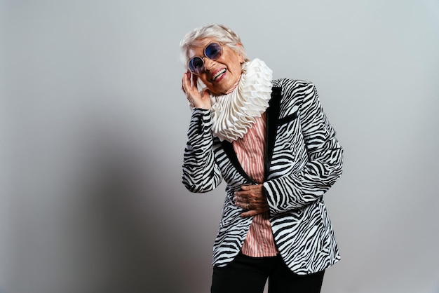 Hermosa y elegante mujer influyente. Abuela fresca posando en el estudio con ropa de moda. Señora mayor feliz celebrando y haciendo fiesta. Concepto sobre antigüedad y estilo de vida