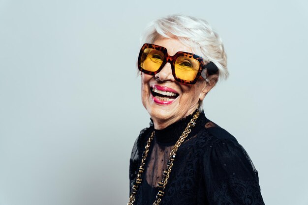 Hermosa y elegante mujer influyente. Abuela fresca posando en el estudio con ropa de moda. Señora mayor feliz celebrando y haciendo fiesta. Concepto sobre antigüedad y estilo de vida