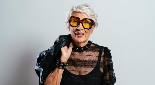 Hermosa y elegante mujer influyente. Abuela fresca posando en el estudio con ropa de moda. Señora mayor feliz celebrando y haciendo fiesta. Concepto sobre antigüedad y estilo de vida