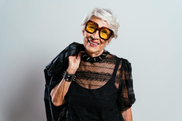 Hermosa y elegante mujer influyente. Abuela fresca posando en el estudio con ropa de moda. Señora mayor feliz celebrando y haciendo fiesta. Concepto sobre antigüedad y estilo de vida